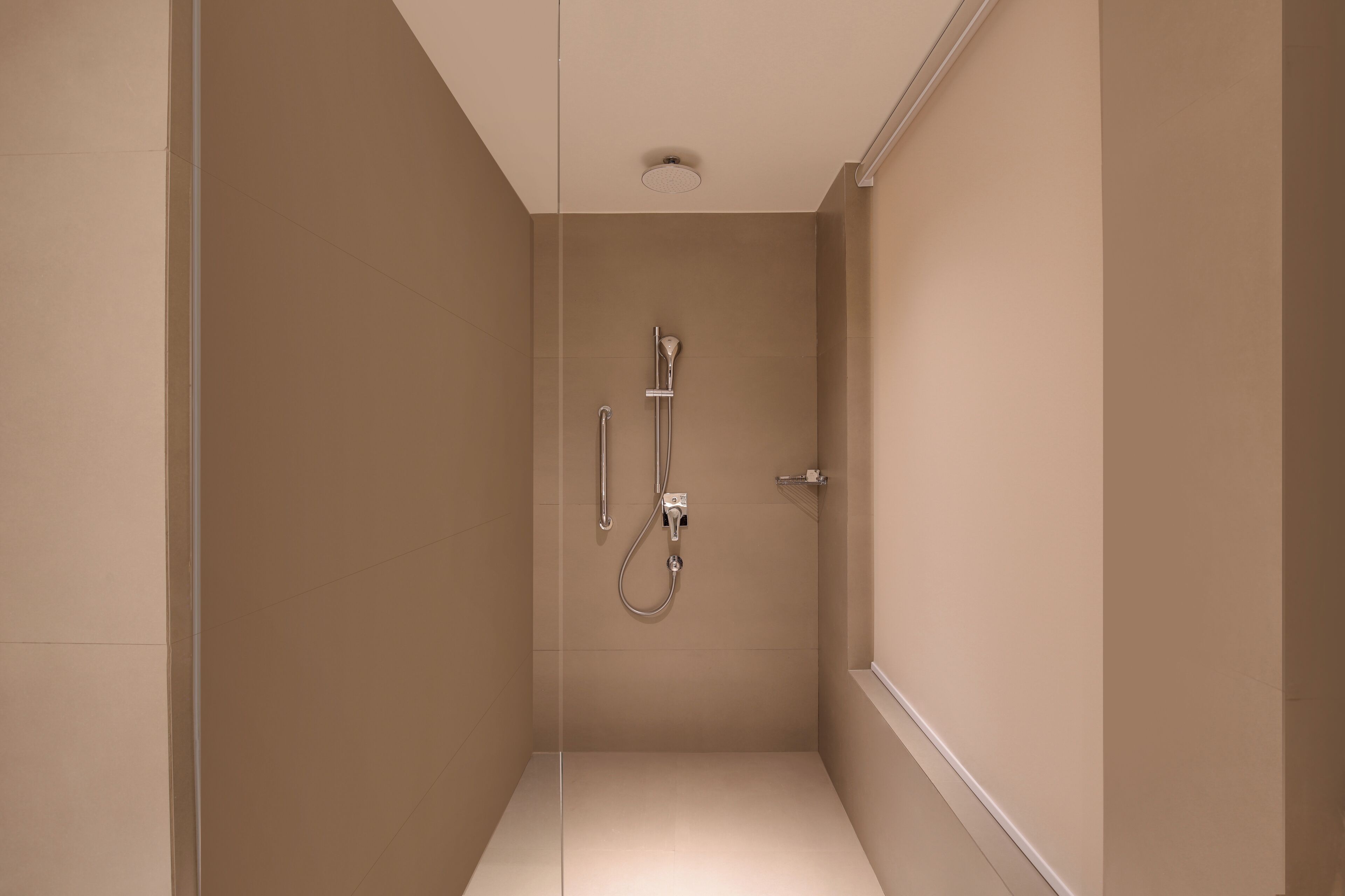 Un baño pequeño y cerrado, con ducha de mano y grifo instalado en la pared.