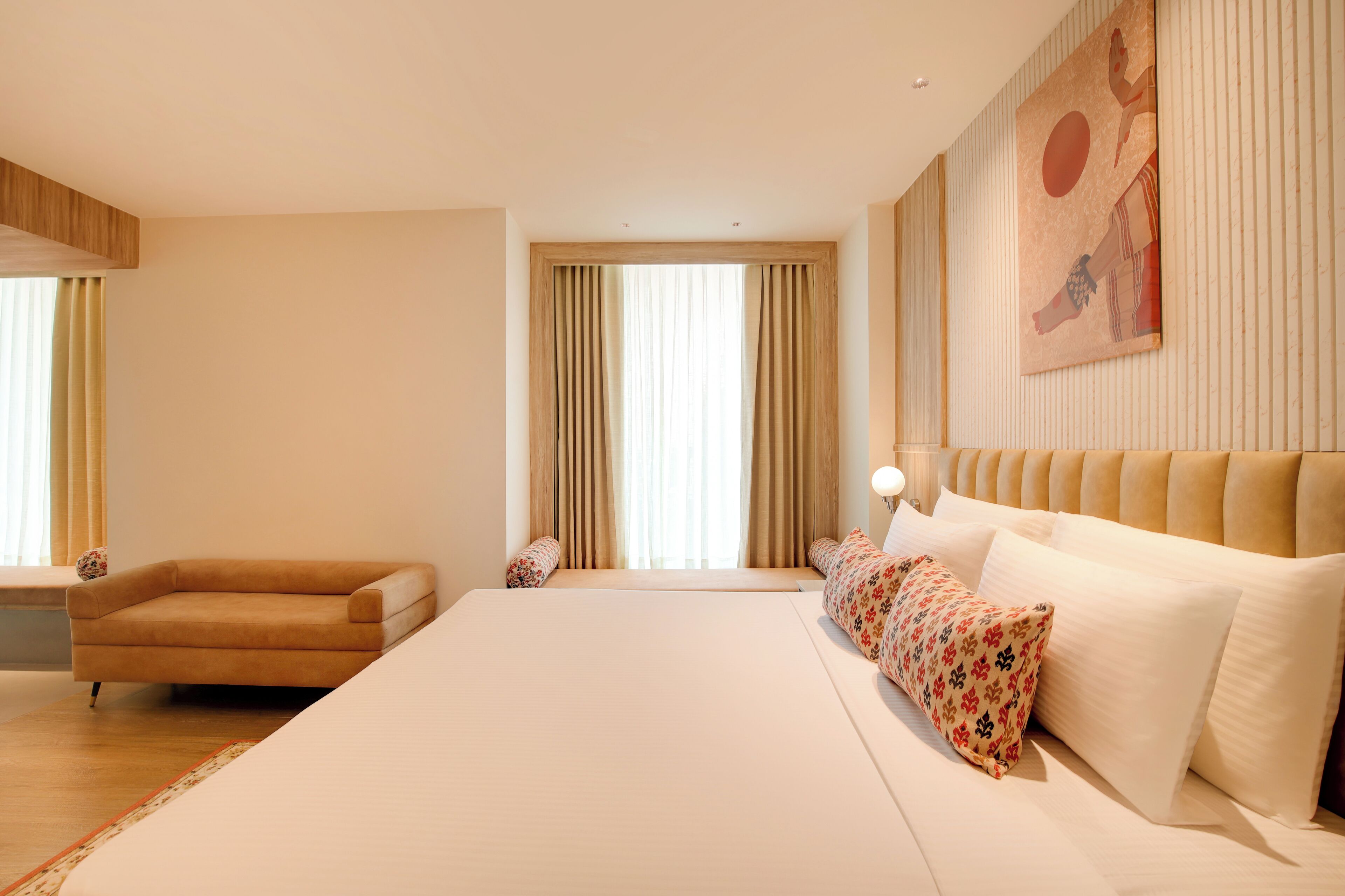 A spacious bedroom with a large bed, a sofa, and a window with curtains.