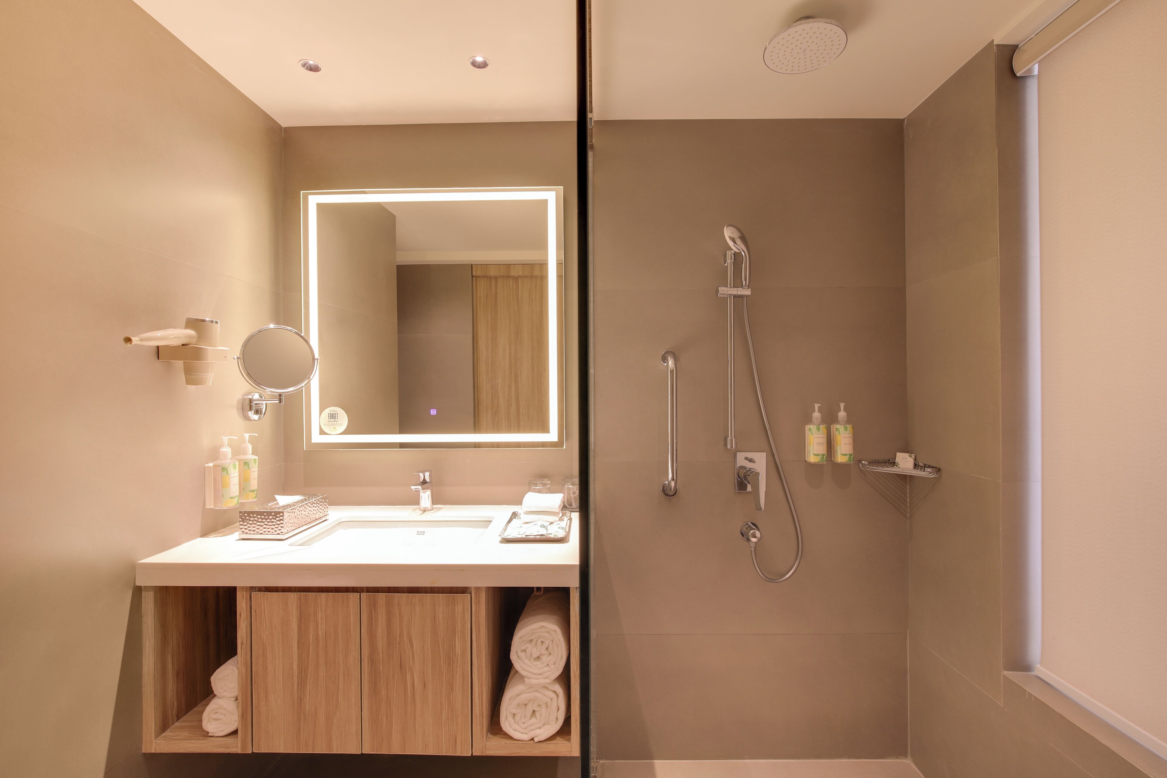 A modern bathroom with a large mirror, a sink, and a shower.