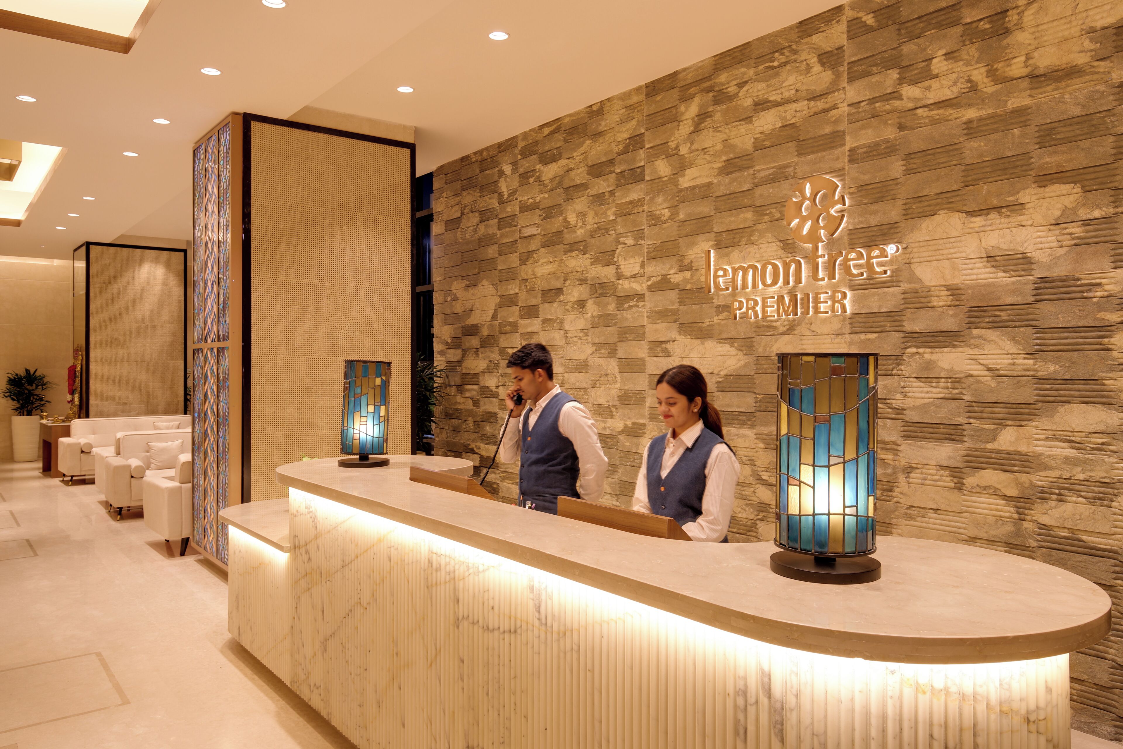 A reception desk with a stone wall backdrop and a sign reading "lemon tree PREMIER".