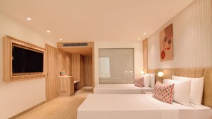 Et moderne hotelværelse med en stor seng, et fjernsyn, et træskab og et stort vindue.