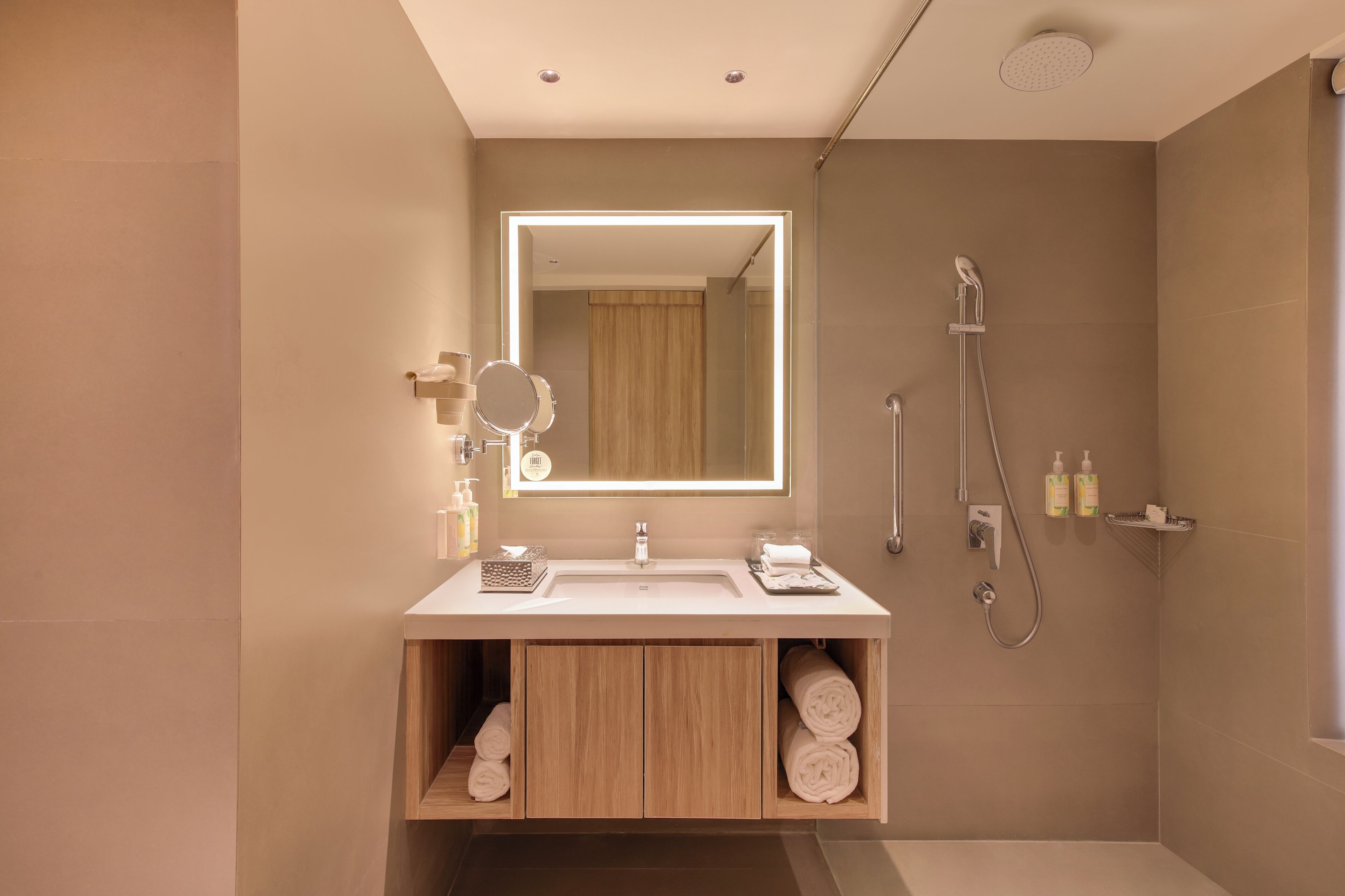 A modern bathroom with a large mirror, a shower, and a vanity with storage.