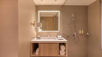 Un baño moderno con un espejo grande, ducha y tocador con almacenamiento.