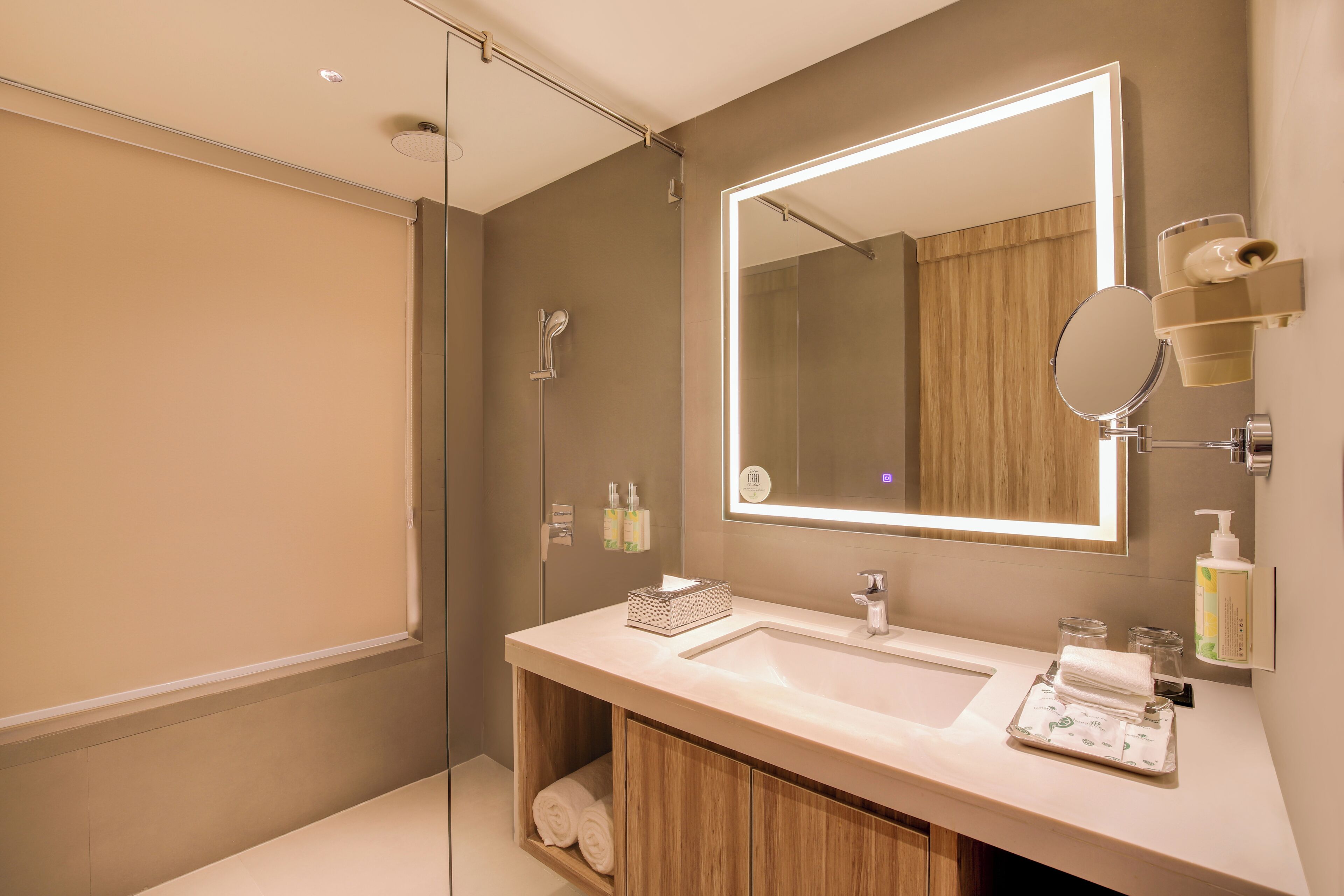 A modern bathroom with a large mirror, a glass shower enclosure, and a wooden vanity.