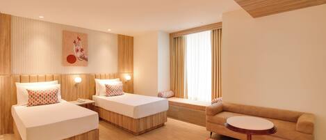 Una habitación de hotel moderna con dos camas, un sofá, una mesita redonda y un ventanal con cortinas.