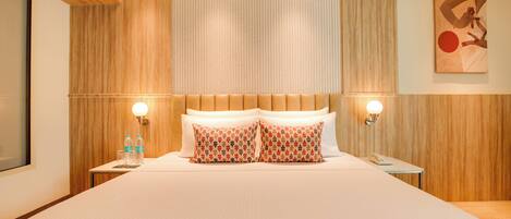 Habitación de hotel con una cama grande, paredes de paneles de madera, dos mesitas de noche con lámparas y un cuadro en la pared.