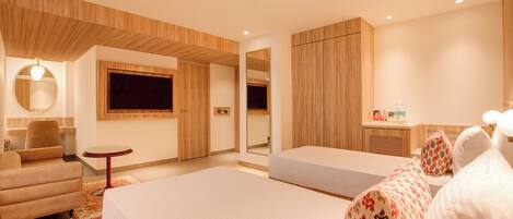 Une chambre d’hôtel moderne avec un grand lit, un canapé, une petite table ronde et un miroir.
