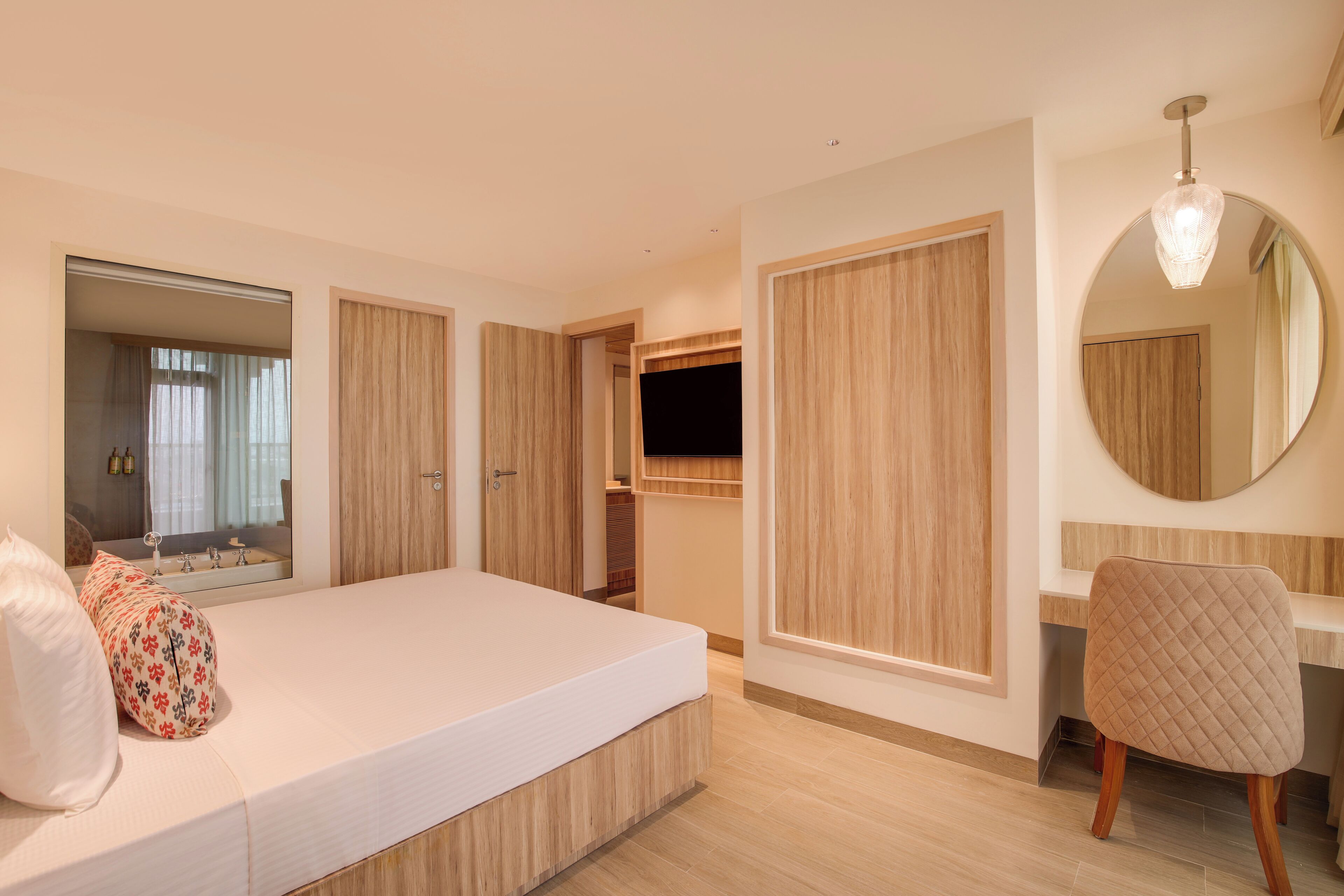 A bedroom with a bed, a mirror, a wardrobe, and a desk.