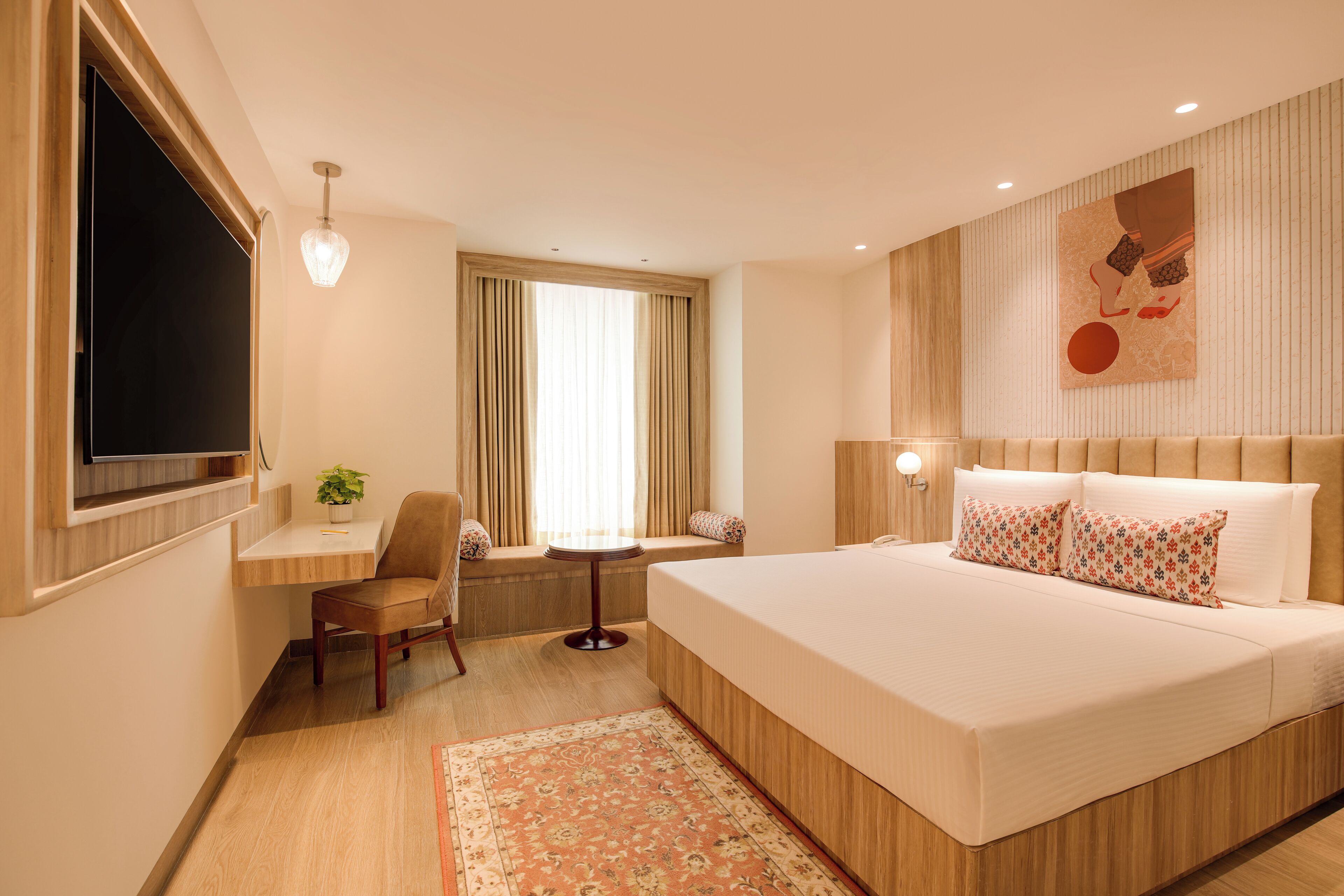 A hotel room with a large bed, a desk, a chair, a TV, and a window with curtains.