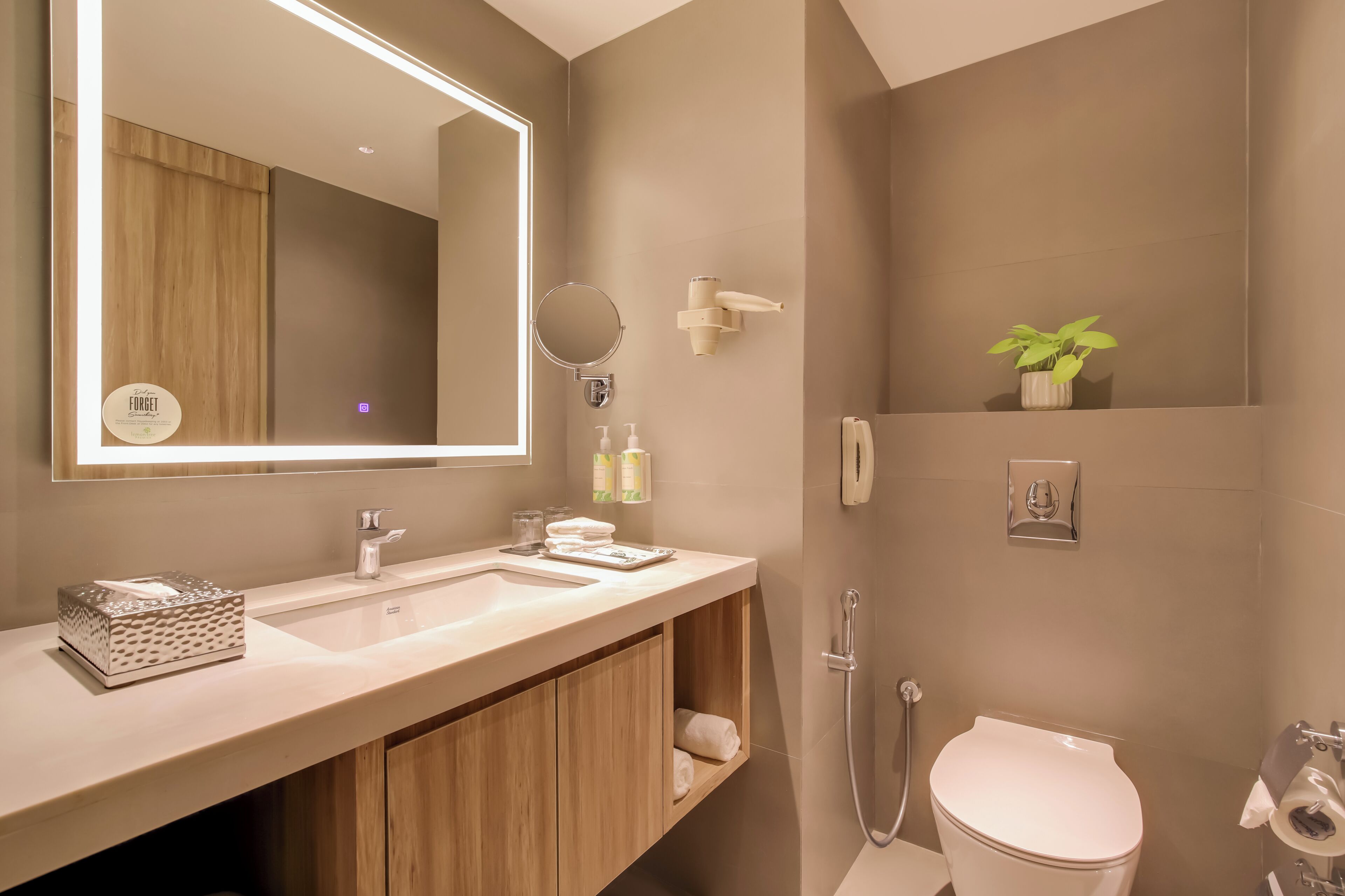 A modern bathroom with a large mirror, dual sinks, a toilet, and a shower.