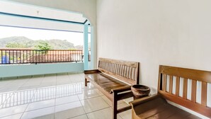 A balcony with a wooden bench and a large pot. - OYO 94780 Blessing Homestay (Surabaya)