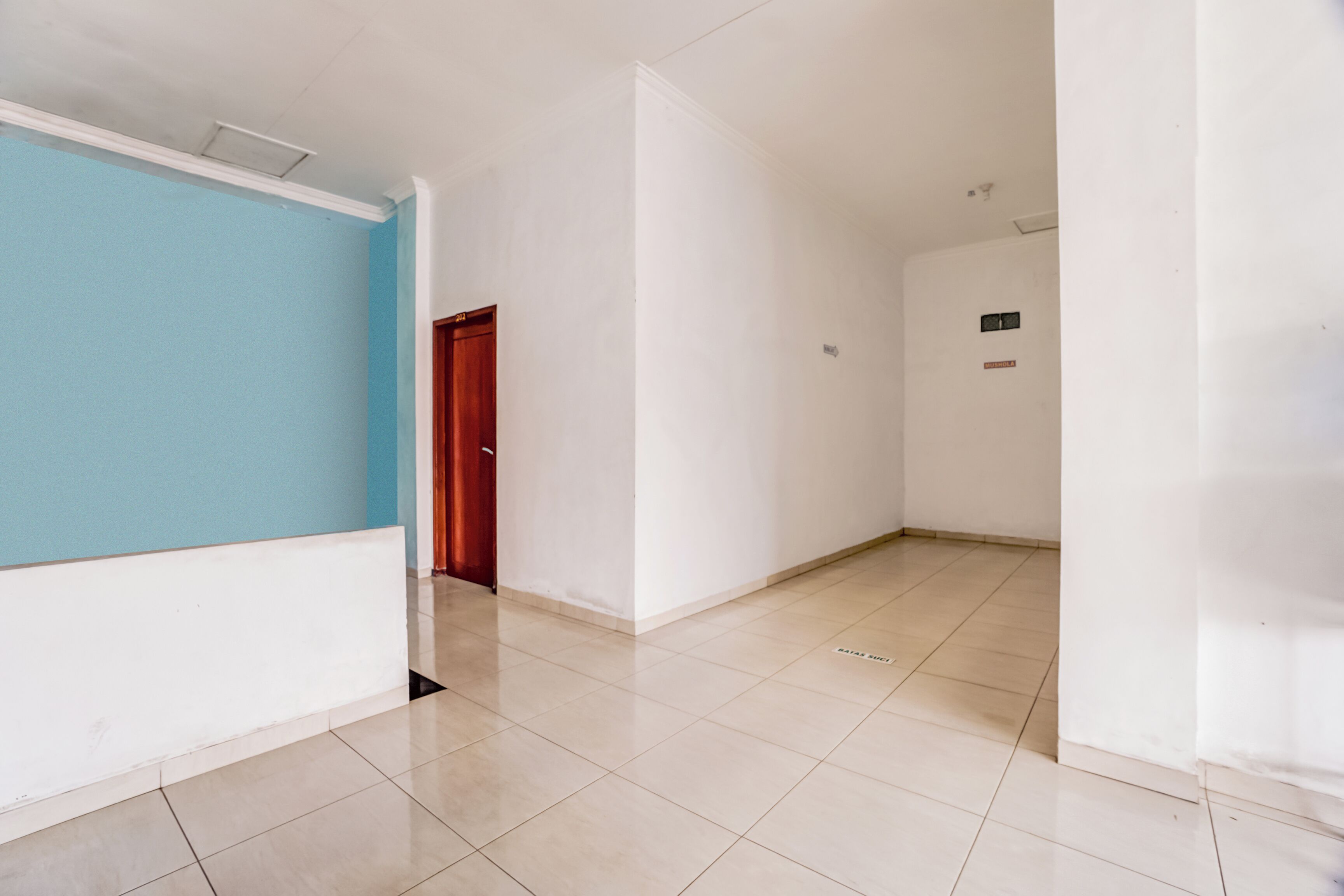 A hallway with a blue wall on one side and a white wall on the other, leading to a door.