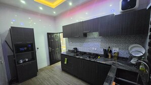 A modern kitchen with dark cabinetry, a gas stove, and a built-in oven. - DF Blessed Apartment (Abuja)