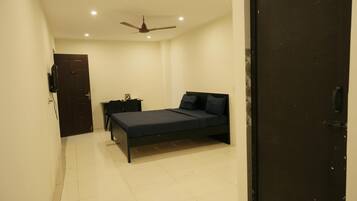 A bedroom with a bed, a nightstand, a ceiling fan, and a door.