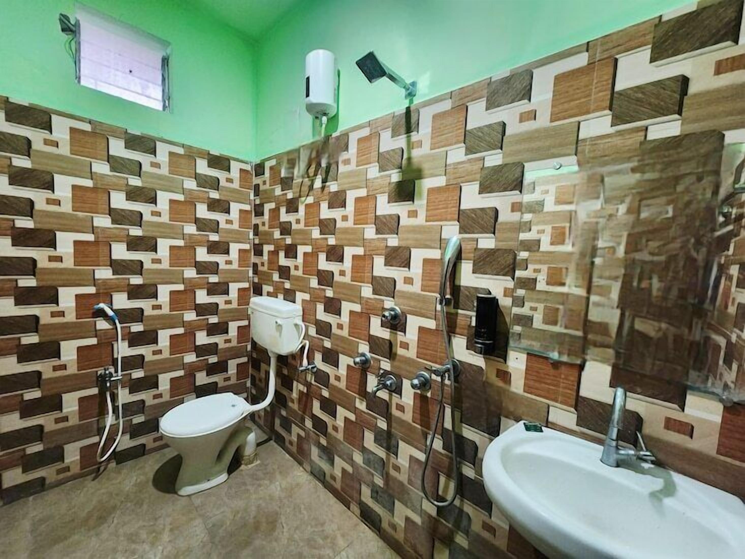 A bathroom with a patterned tile wall, a toilet, a sink, and a shower.