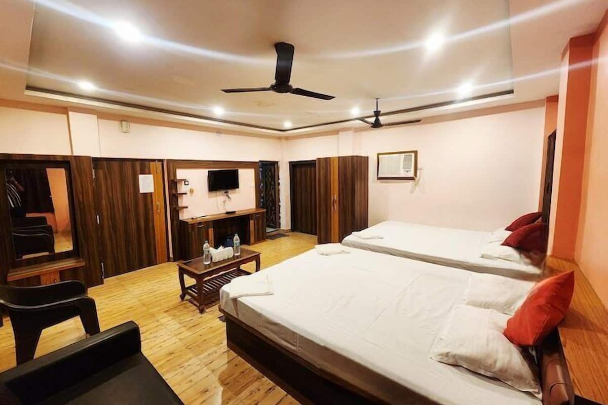 Una habitación de hotel con dos camas, televisión, escritorio y armario.