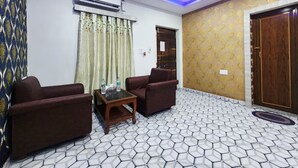 A living room with two sofas, a coffee table, patterned wallpaper, a ceiling fan, and an air conditioning unit. - Resort Garden Retreat (Kanthi)