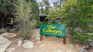 A sign for 'The Cottages at Forest Trails' with a rustic wooden structure in the background. - Sagewood Cottage: A private home with comfort, style, amazing amenities, and Tranquil location! (Prescott)