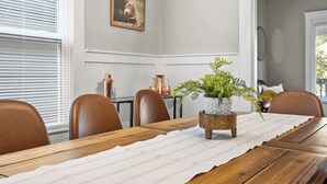 A dining room with a wooden table, brown chairs, a white tablecloth, and a potted plant. - Spacious Home for Groups with Firepit & Backyard (Louisville)