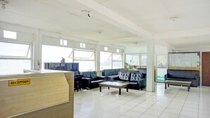 A reception area with a reception desk, several sofas, and a large window providing natural light.