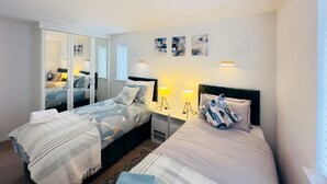 Una habitación de hotel moderna con dos camas, un espejo grande y obras de arte en las paredes.