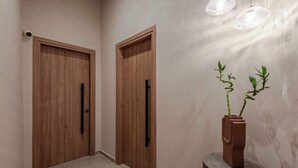 A hallway with wooden doors and a potted plant on a wooden stool.