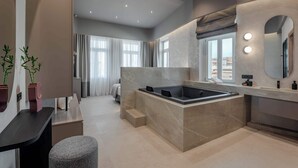 A modern bathroom with a freestanding bathtub, a vanity with a mirror, and a seating area.