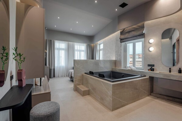 Une salle de bain moderne avec une baignoire sur pieds, un meuble-lavabo avec un miroir et un coin salon.