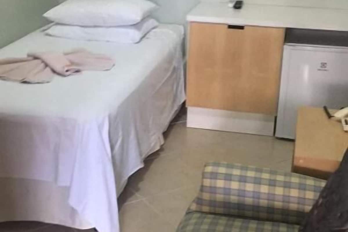 Ein Schlafzimmer mit Bett, Nachttisch, Stuhl und einem kleinen Schreibtisch mit Computer.