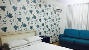 Une chambre à coucher avec un lit, une table de chevet, un canapé bleu et un papier peint à motifs floraux.