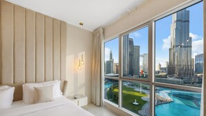 Une chambre d’hôtel avec un grand lit, une table de chevet, une lampe et une vue sur le paysage urbain et un plan d’eau.