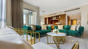 Un salon moderne avec un canapé vert, une table basse ronde et un lit dont le cadre est doré.