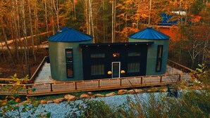 Eine moderne Hütte mit zwei Gebäuden mit blauen Dächern, einer Holzdiele und einem Kiesweg.