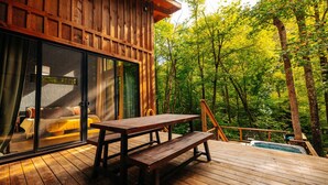 Een houten terras met een picknicktafel en een jacuzzi.