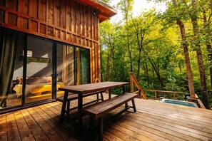 Une terrasse en bois avec une table de pique-nique et un jacuzzi.