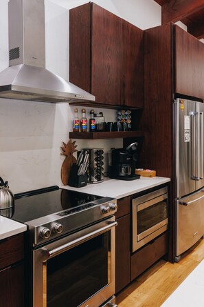Une cuisine moderne dotée d’appareils électroménagers en acier inoxydable, de meubles en bois et d’un plan de travail blanc.