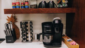 Een aanrecht met een koffiezetapparaat, een kruidenrek en flessen Torani siroop.