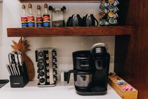 Un plan de travail de cuisine avec une machine à café, un étagère à épices et des bouteilles de sirop Torani.