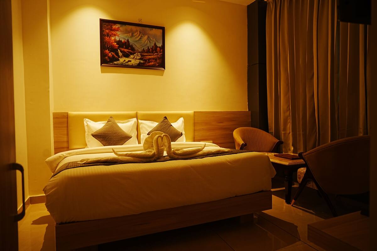 Une chambre d’hôtel avec un grand lit, une chaise et un tableau au mur.