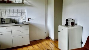 Et lille køkken med en hvid bordplade, en brødrister og en kaffemaskine.