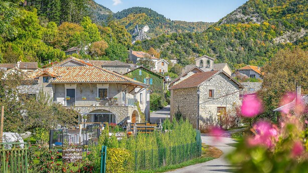 Un village aux maisons en pierre, une route et une montagne en toile de fond.