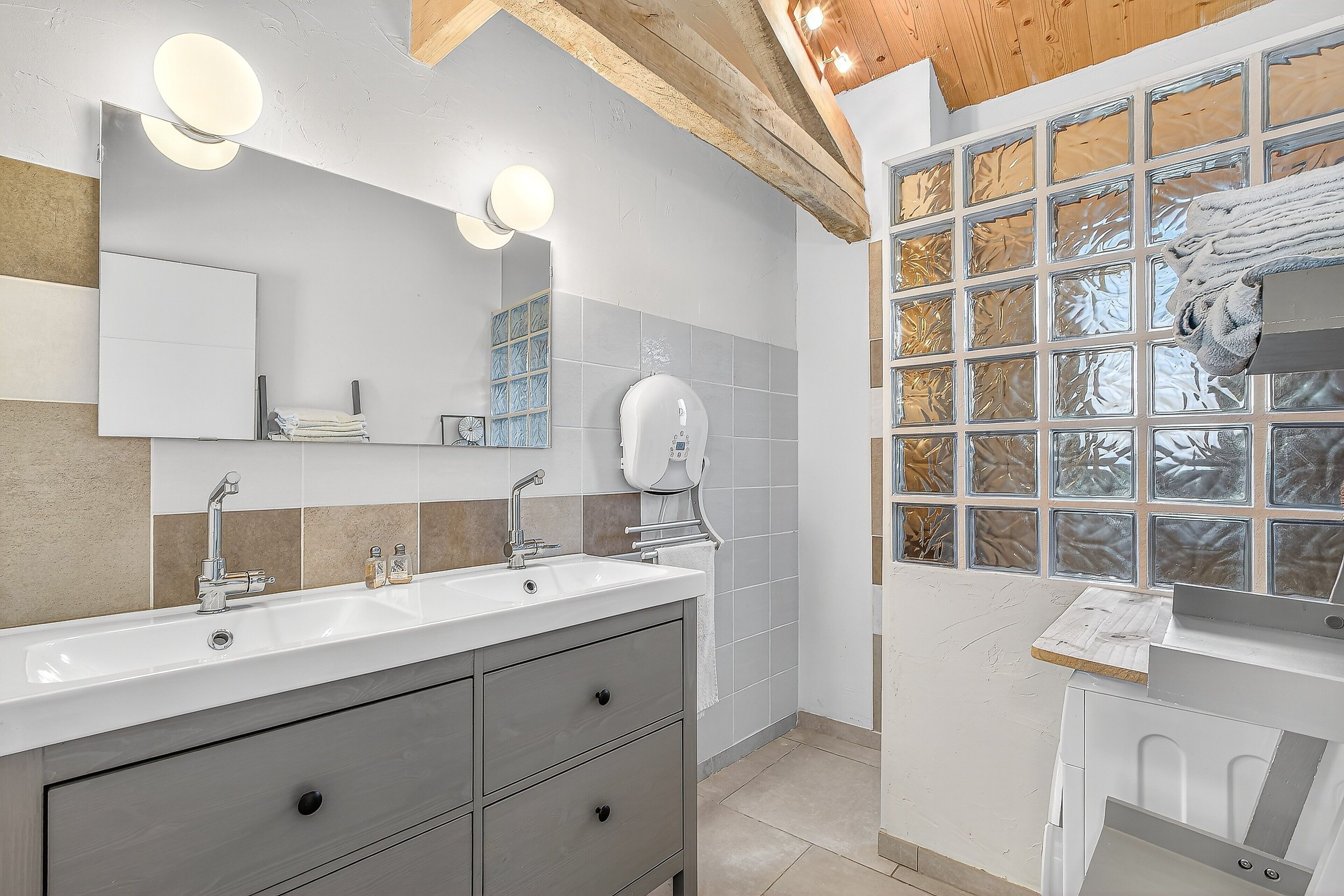 Een moderne badkamer met een grote spiegel, twee wastafels en een raam met etspray glas.