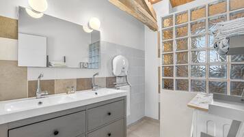 Een moderne badkamer met een grote spiegel, twee wastafels en een raam met etspray glas.