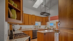 Uma cozinha com armários de madeira, bancada de mármore e luminária pendente.