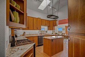 Une cuisine avec des meubles en bois, un plan de travail en marbre et un luminaire suspendu.
