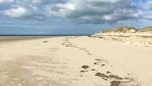 A wide sandy beach with dunes in the background and a partly cloudy sky. - Charming stone house with garden near the sea (Quettreville-sur-Sienne)