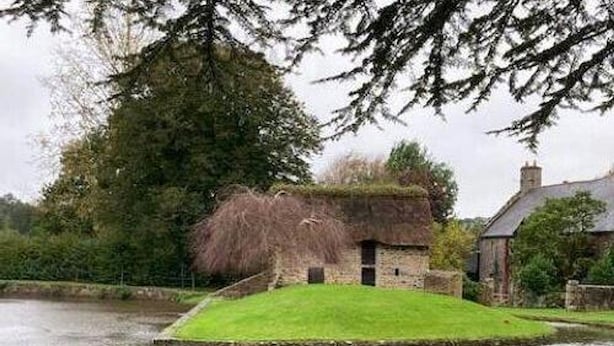 A rustic house with a thatched roof, a small pond, and a grassy area in front. - Charming stone house with garden near the sea (Quettreville-sur-Sienne)