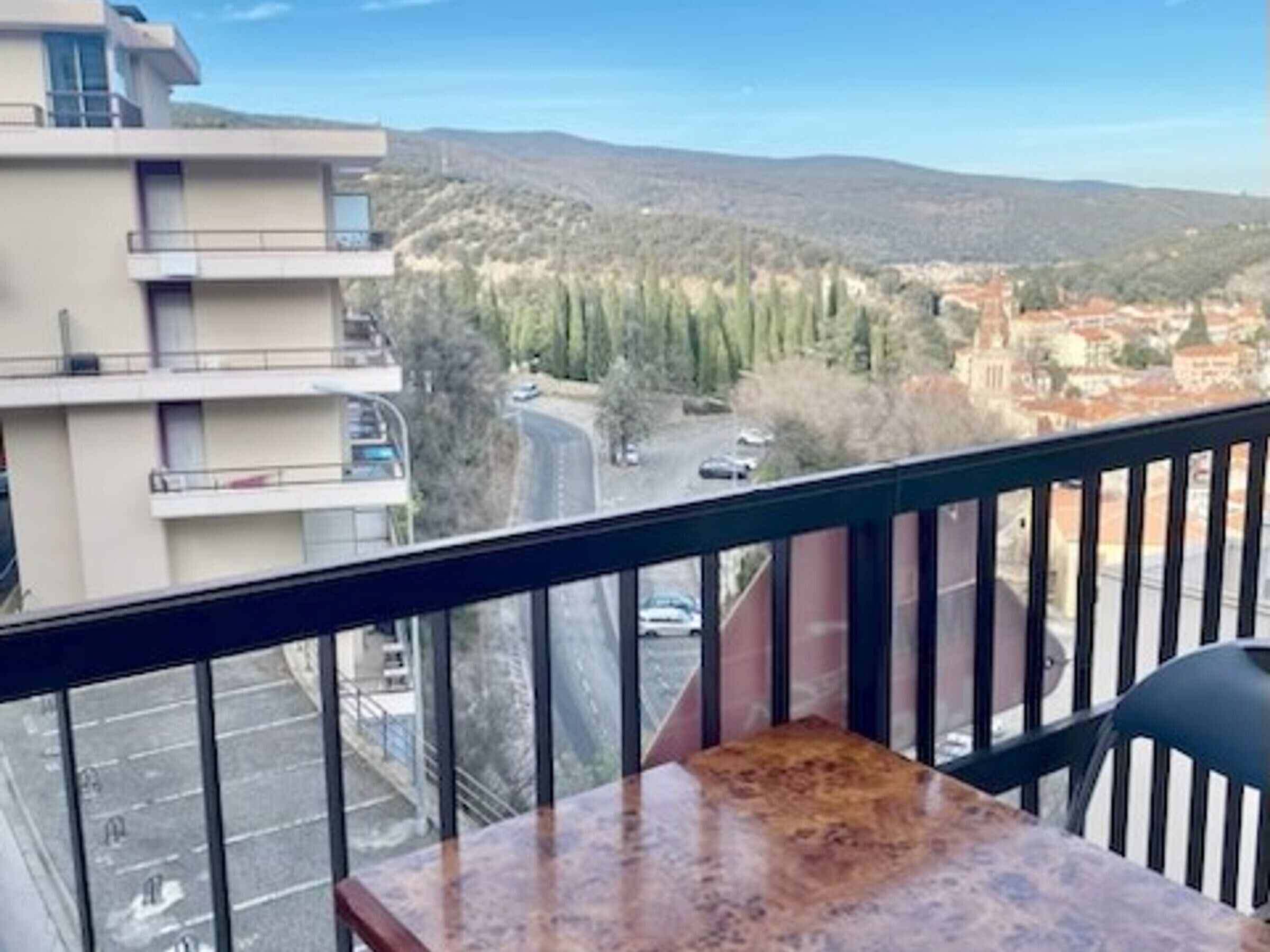 Un balcon offrant une vue sur le paysage urbain, avec des bâtiments et des arbres.