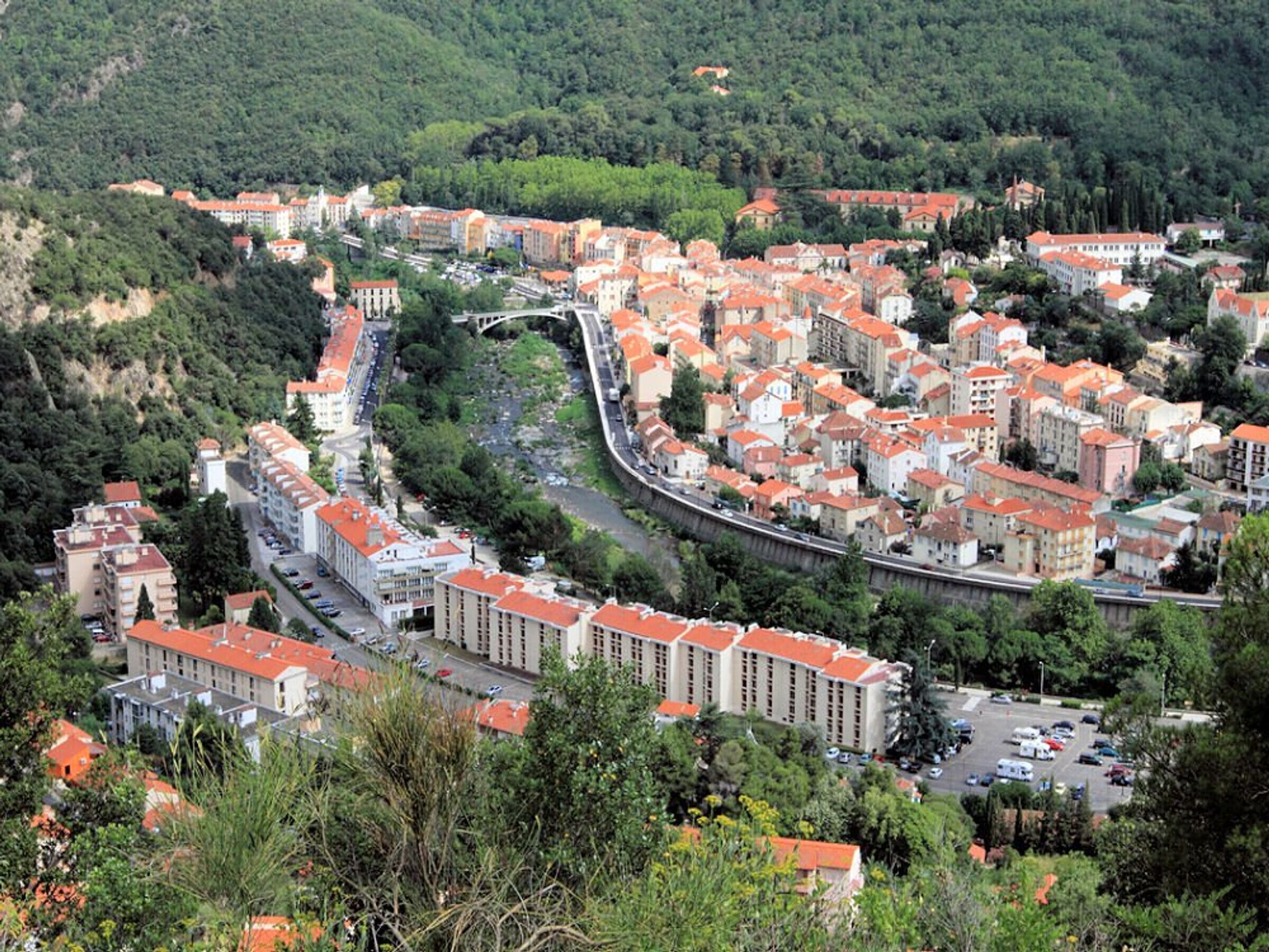A densely packed urban area with a mix of residential and commercial buildings, featuring a curved road and a bridge.