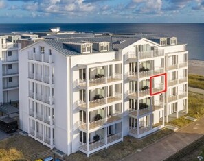 Um hotel com vários andares, varandas, área de estacionamento e vista para o mar.